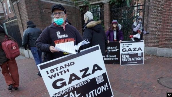 FILE - George Stevens of Cambridge, Mass., hands out leaflets to passers-by near an entrance to Harvard University, Dec. 12, 2023, in Cambridge, while joining with pro-Palestinian demo<em></em>nstrators during a protest held to call for an end to the war in Gaza.