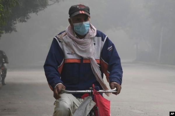 A cyclist wears a mask to protect himself against smog as he heads to work in Lahore, Pakistan, Nov. 8, 2023.