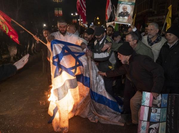 Iranian protesters are carrying a portrait of the former commander of the IRGC and a Yemeni flag, as they burn an Israeli flag during an anti-U.S. and anti-British protest in downtown Tehran, Iran, on Jan. 12, 2024. 