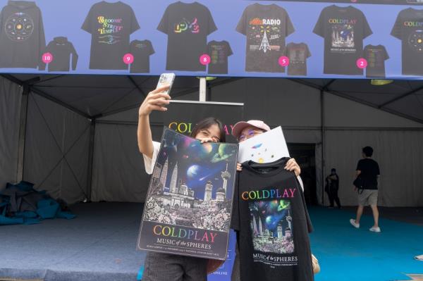 Fans take a picture with Coldplay merchandise at Bukit Jalil Natio<em></em>nal Stadium in Kuala Lumpur on November 22, 2023. — Picture by Shafwan Zaidon