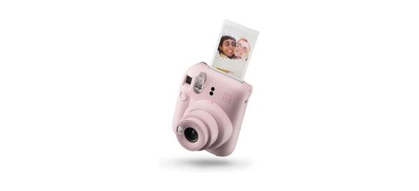 Fujifilm Instax Mini 12 Instant Camera in a light pink color with a picture being printed from it