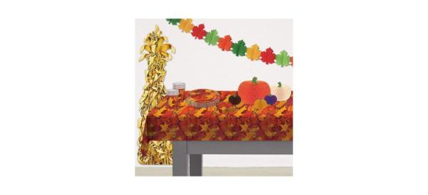 A table with a plastic tablecloth that has a fall leaves design