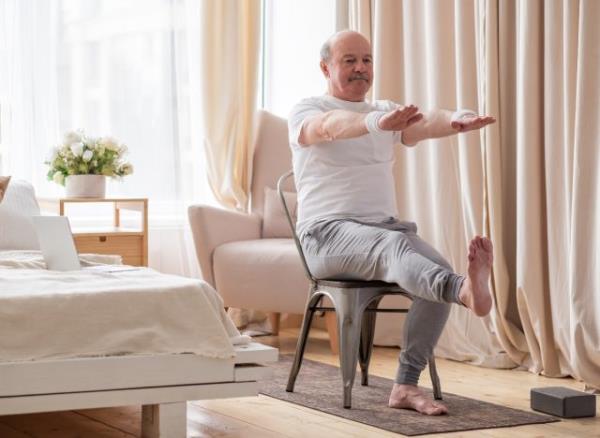 senior man doing seated leg extension, demo<em></em>nstrating exercises for seniors to prevent falls