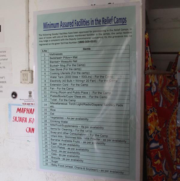 A flex banner at a relief camp promising minimum assured facilities. Camp residents across the state, however, say o<em></em>nly a few of the said facilities are provided to them now as the ethnic strife completes a full year on May 3.