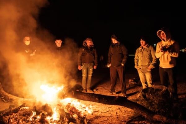 Migrants burn wood to keep warm as they wait to be transported by border patrol agents in Jacumba Hot Springs, California, on 10 November 2023.