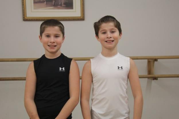 Two twin brothers, both 12 years old, stand next to each other and smile.
