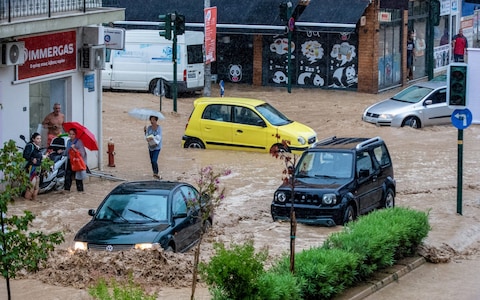 Cars drive in rising waters, following a flash flood during a storm in the city of Volos, Greece