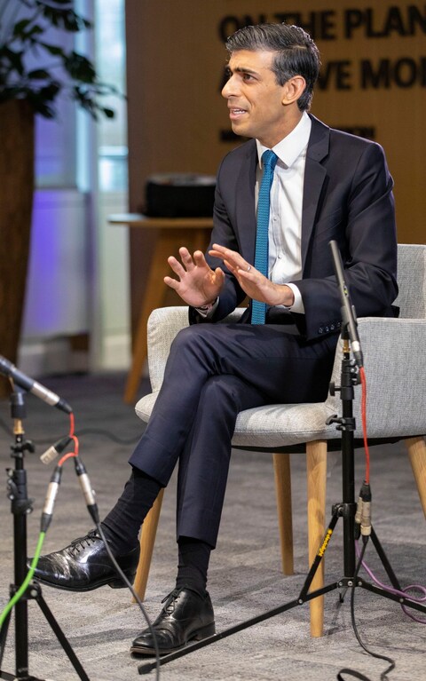 Rishi sits cross-legged, his ankles and lower leg very much on display